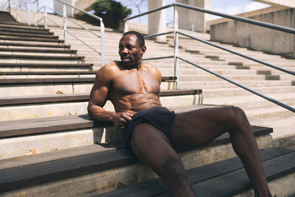 homem africano muscular descansando nas escadas - Foto, Imagem