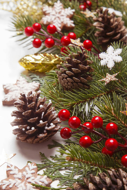 クリスマスの装飾。クリスマスツリーの枝、赤い果実と白い背景に雪の結晶クッキー. - 写真・画像