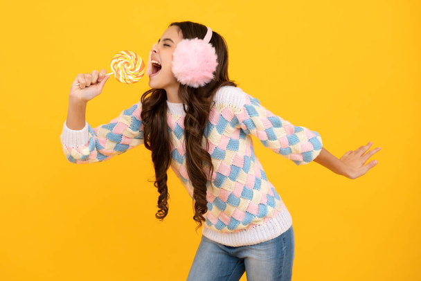 Excited face. Teen girl hold lollipop caramel on yellow background, candy shop. Teenager with sweets suckers. Amazed expression, cheerful and glad - Фото, зображення