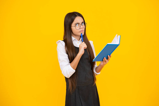 Back to school. Teenager schoolgirl with book ready to learn. School girl children on isolated yellow studio background. Thinking face, thoughtful emotions of teenager girl - Photo, Image
