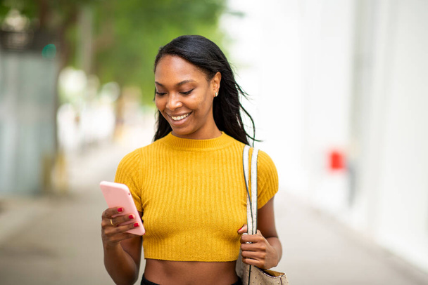 Krásná africká americká žena textové zprávy pomocí mobilního telefonu venku ve městě - Fotografie, Obrázek