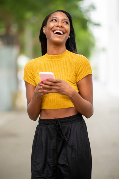 Mujer divirtiéndose mientras usa el teléfono móvil al aire libre en la ciudad - Foto, Imagen