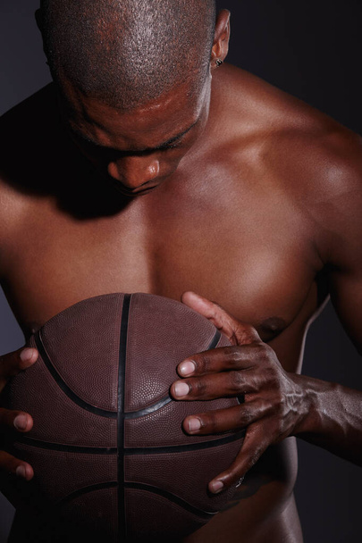 Soustředěný před zápasem. Studio záběr zaostřený mladý basketbalista stojící na černém pozadí - Fotografie, Obrázek