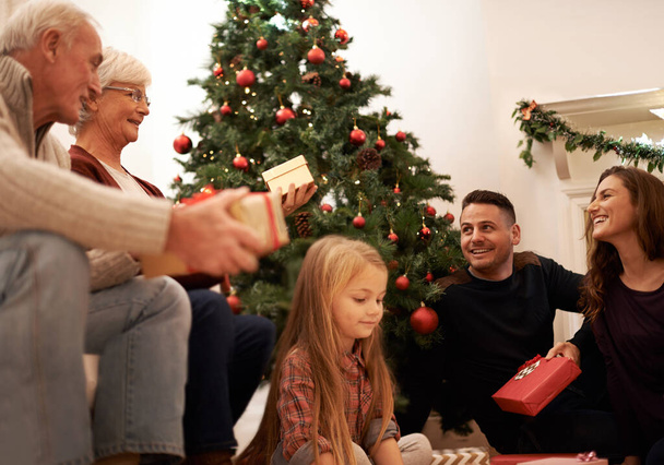 Wypełniona radością dawania. wielopokoleniowa rodzina wymieniająca się prezentami na Boże Narodzenie - Zdjęcie, obraz