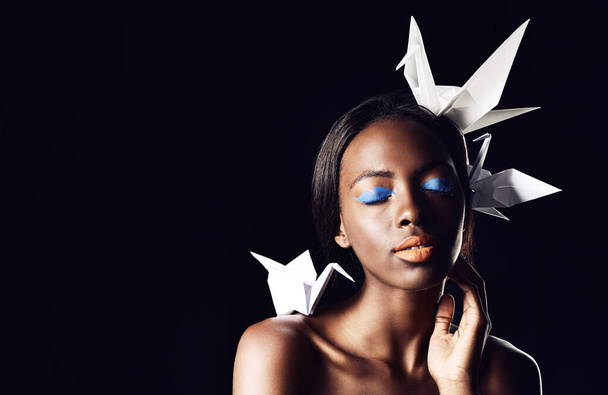 Es una belleza africana. una hermosa mujer étnica posando con pájaros de origami en su cabeza y hombros - Foto, Imagen