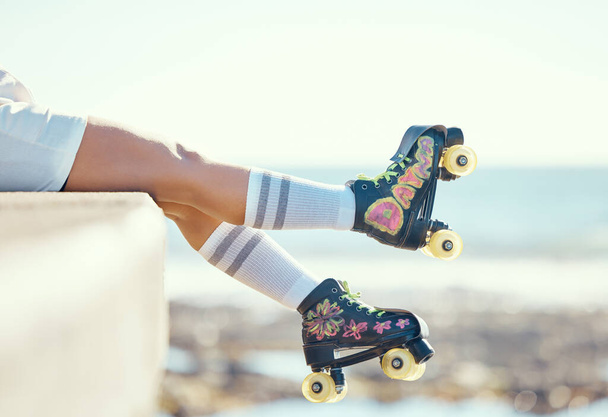 Relax roller skate woman legs at beach, ocean harbor or sea water with holiday fun, freedom and adventure travel. Feet of sports athlete or skater girl with skating shoes for summer outdoor journey. - Photo, image