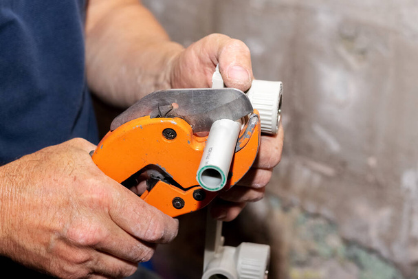 Hydraulik używa specjalnych nożyczek do przecięcia rury polipropylenowej podczas montażu rury wodnej - Zdjęcie, obraz