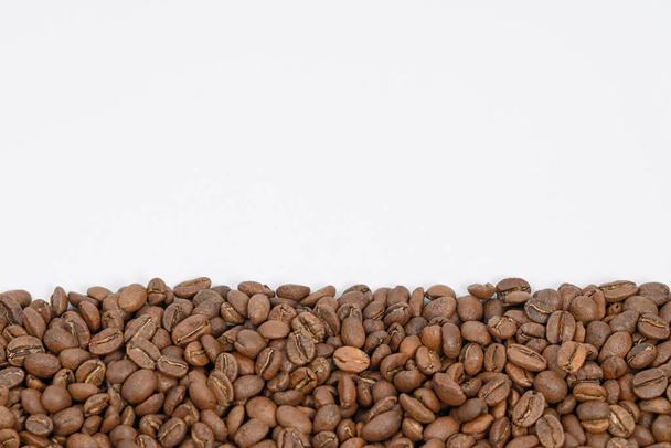 Kávová zrna v jedné široké řadě na bílém pozadí, místo pro nápis a reklamu, kopírovací prostor. - Fotografie, Obrázek