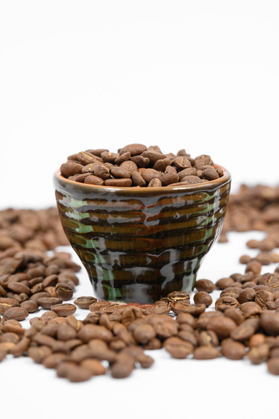 Ароматні смажені кавові зерна на білому тлі та маленька чашка, енергетичний напій
. - Фото, зображення