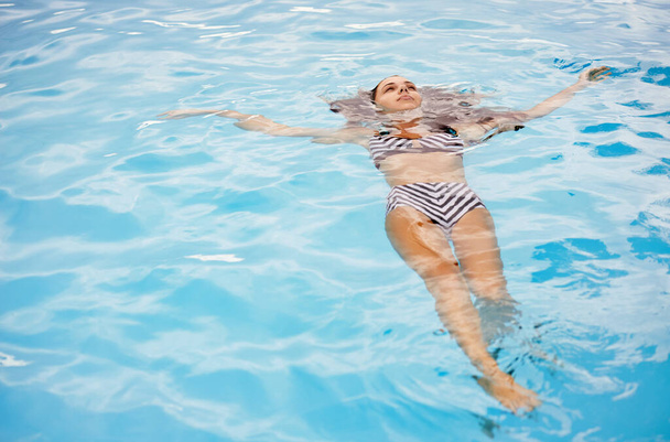 逃げるために私の好きな場所。きれいなプールに浮かんでいる美しい若い女性の完全な長さのショット - 写真・画像