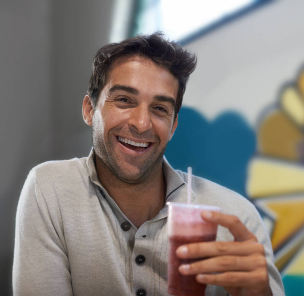 Mmm, refreshing. Portrait of a handsome man drinking a smoothie at a restaurant - Fotó, kép