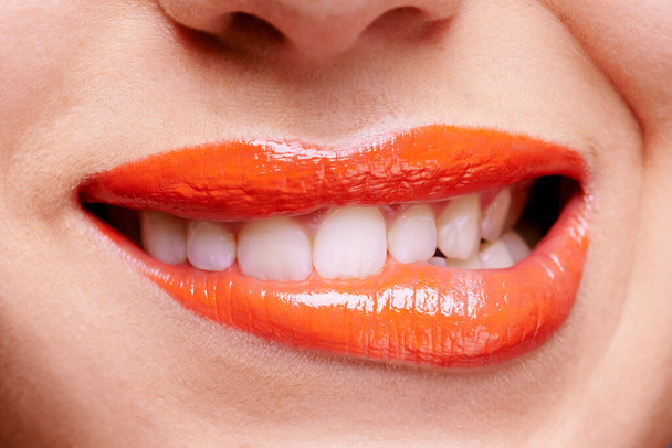 Shes anything but ordinary in orange. a woman biting her orange colored lips - Fotografie, Obrázek