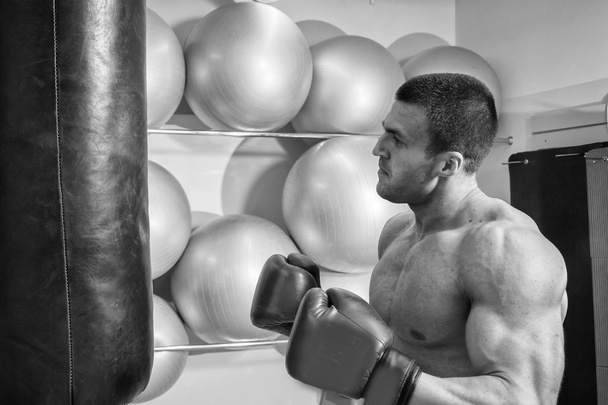 Мускулистый человек в боксёрских перчатках в спортзале
 - Фото, изображение