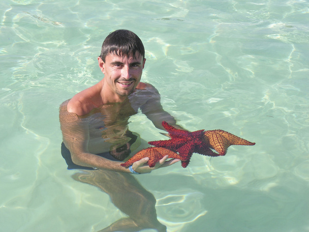 Man with 3 Starfishes in the Caribbean Sea - Photo, Image