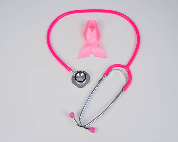 Pink ribbon and stethoscope on a white background. The concept of the fight against breast cancer - Фото, зображення