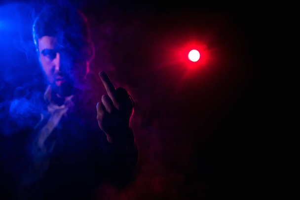 Close up photo of man showing middle finger on pink and black background. Concept of man showing middle finger. - 写真・画像