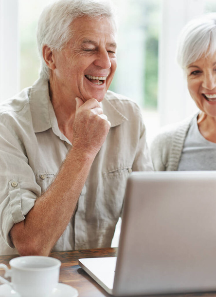 Ponerse al día con los niños. Una alegre pareja de ancianos teniendo un video chat en un portátil - Foto, Imagen