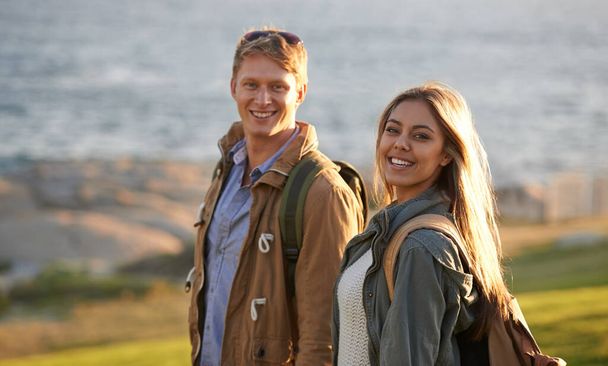 Познать мир вместе. Портрет молодой пары, стоящей на краю насыпи с видом на океан - Фото, изображение