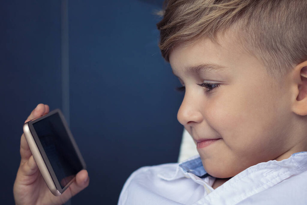 Kleine jongen die tekenfilms kijkt op het internet via een smartphone. Kind met mobiele telefoon. - Foto, afbeelding