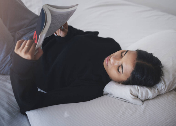 Woman, student and reading book in bedroom for relax, learning and studying at home. Young teenager, college girl and person rest with books in bed for education, knowledge and fiction novel story. - Foto, afbeelding