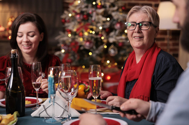 Woman celebrating christmas with family together, sitting at festive dinner table with mom at home party. Mother and daughter eating home cooked xmas food in decorated beautiful place - Photo, Image
