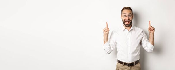 幸せな男性起業家ビジネス服で、指を指してプロモーションを提示し、白い背景の上に立って. - 写真・画像