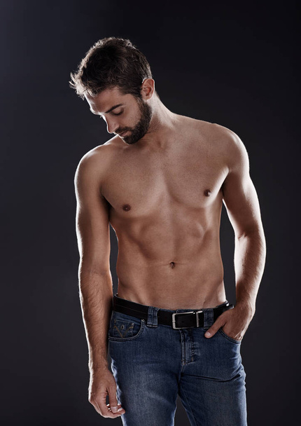 Lichaamsvertrouwen. een knappe man staat shirtloos tegen een zwarte achtergrond - Foto, afbeelding