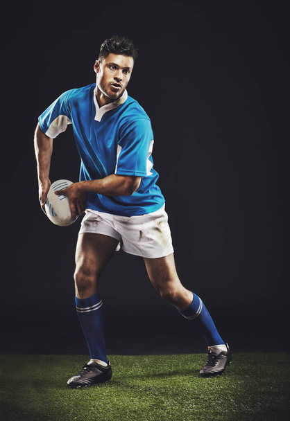 Rugby- είναι ένα τραχύ και δύσκολο παιχνίδι. Full length studio shot ενός νεαρού παίκτη ράγκμπι στο γήπεδο - Φωτογραφία, εικόνα