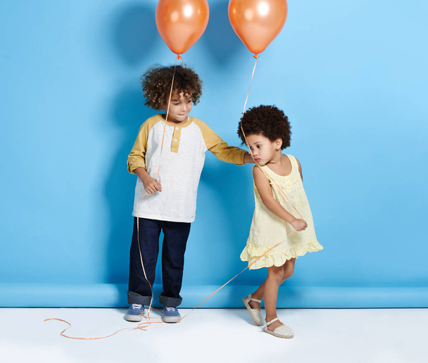 Não posso tocar nisto. uma menina e menino segurando um balão sobre um fundo azul - Foto, Imagem