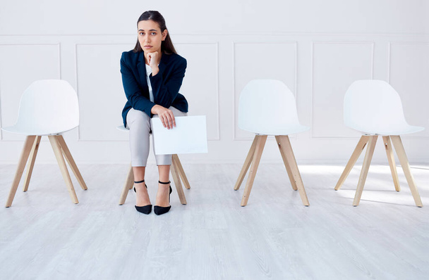 Portrait business woman waiting for an interview or stress applicant sitting alone. Sad or nervous corporate professional holding resume in line for job opening, vacancy and opportunity in office. - 写真・画像