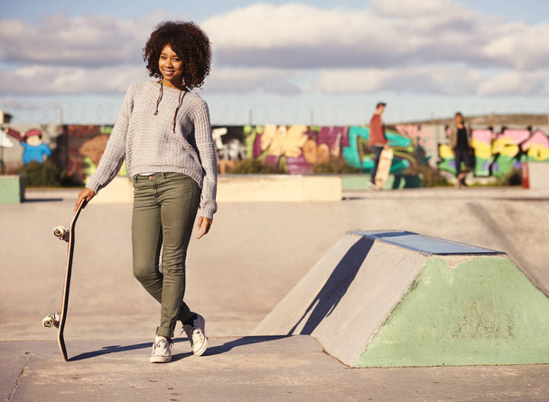 Miért sétálnál, ha tudsz korcsolyázni? Egy fiatal nő gördeszkázik a városban. - Fotó, kép
