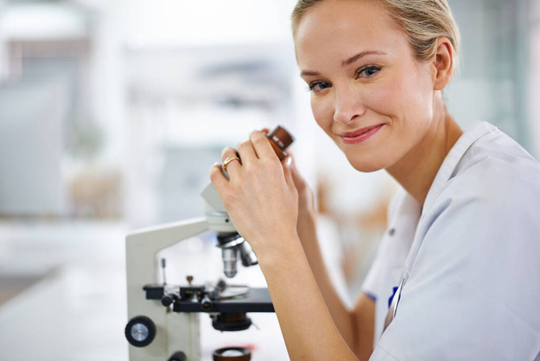 Beauty and brains. a beautiful woman in a laboratory working with a microscope - Photo, Image