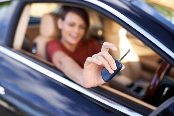 Przejedźmy się tym. Zbliżenie kobiety siedzącej w samochodzie trzymającej kluczyki do kamery - Zdjęcie, obraz