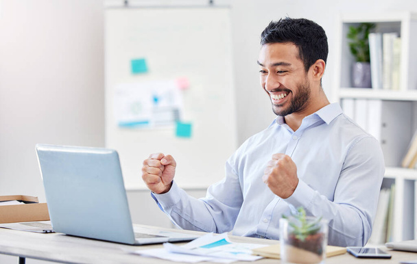 Motivatie, succes en ja met een zakenman in viering en werken aan een laptop bij zijn bureau in het kantoor. E-mail, goed nieuws en glimlach met een jonge en gelukkige mannelijke werknemer juichen op het werk. - Foto, afbeelding