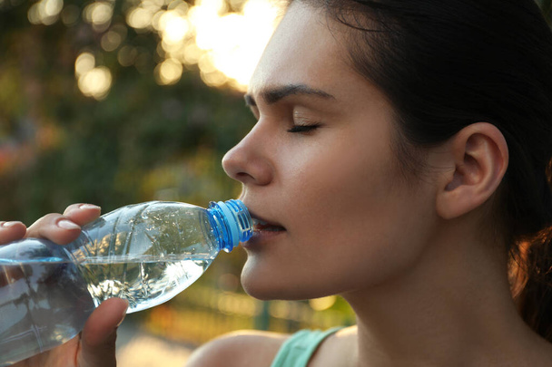 Giovane donna che beve acqua all'aperto, primo piano. Bevanda rinfrescante
 - Foto, immagini