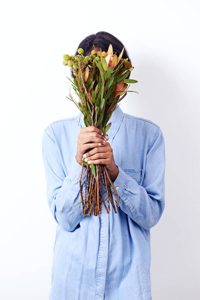 Déesse de la nature. Plan studio d'une jolie jeune femme ethnique tenant un bouquet de fleurs devant son visage - Photo, image