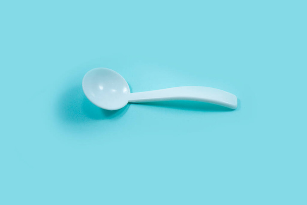 white plastic teaspoon isolated on a turquoise - Fotografie, Obrázek