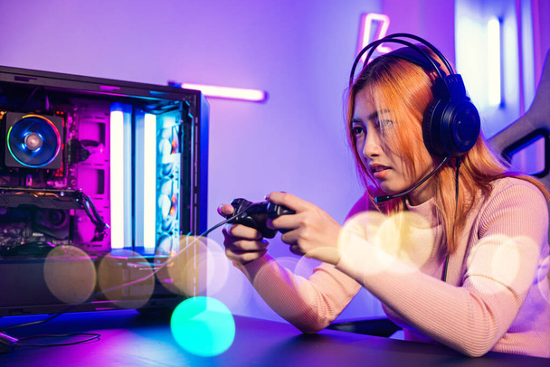 Woman wear gaming headphones playing live stream esports games console at home, Gamer using joystick controller for virtual tournament plays online video game with computer neon lights, Esport concept - 写真・画像