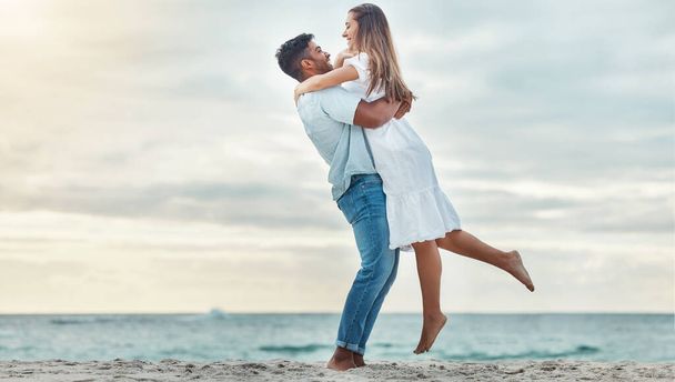 Szczęśliwa para na plaży podnieść i przytulić, aby uczcić miłość na romantyczny zachód słońca tropikalny ocean wody Bali luksusowe wakacje podróży lub wakacje. Kobieta i mężczyzna randki i uroczystości na zaręczyny ogłoszenie. - Zdjęcie, obraz