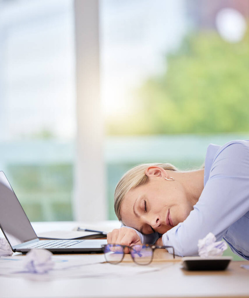 Dormir, agotarse y cansarse con una mujer de negocios durmiendo en su escritorio en la oficina en el trabajo. Salud mental, exceso de trabajo y horas extras con una empleada madura acostada en su escritorio con los ojos cerrados. - Foto, imagen