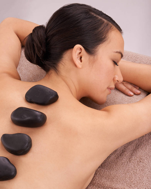 Calmando piedras. una mujer joven disfrutando de una terapia de piedra caliente - Foto, imagen