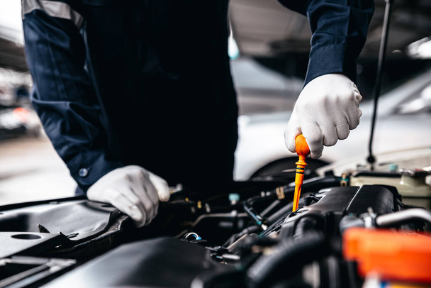 Mechanik sprawdzanie poziomu oleju w silniku w warsztacie garażowym, Samochodowe usługi samochodowe i koncepcja kontroli konserwacji. - Zdjęcie, obraz