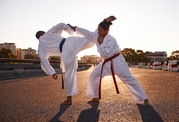 Aiming for her head. Two sportspeople facing off and practicing their karate while wearing gi - Fotó, kép