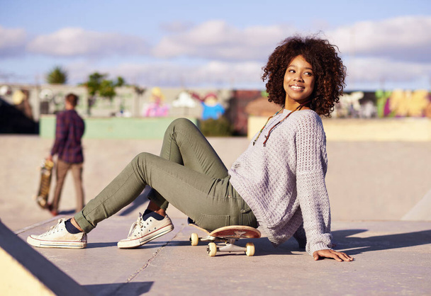 Free to be me at the skatepark. a young woman sitting on her skateboard in a skatepark - 写真・画像