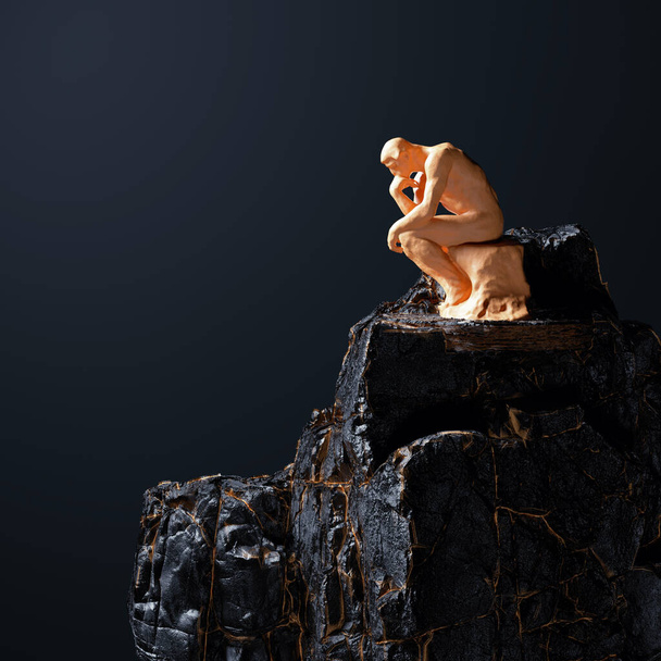 Bedachtzame gouden man zittend op een donkere rots. Moeilijke beslissing en twijfelachtig concept. Dit is een 3D-weergave illustratie. - Foto, afbeelding
