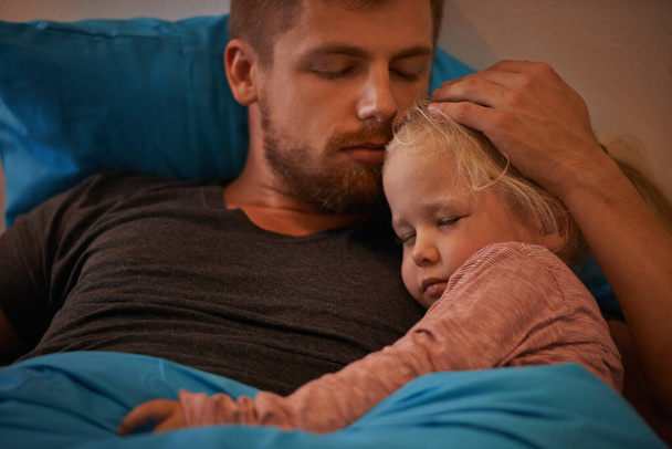 Предан своей маленькой девочке. Маленькая девочка спит в руках отцов в постели - Фото, изображение