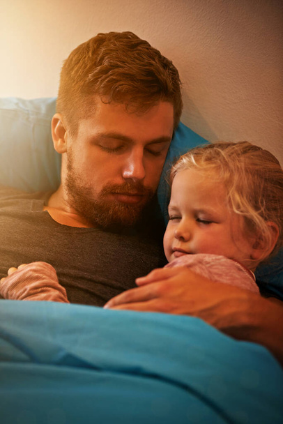 They drifted off to dreamland together. A little girl asleep in her fathers arms in bed - Fotoğraf, Görsel