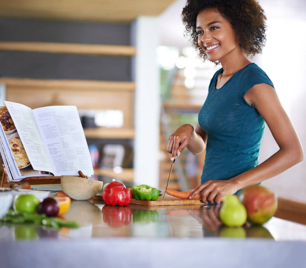 Létrehozása egy finom étel a semmiből. Egy fiatal nő főz egy receptkönyvből. - Fotó, kép
