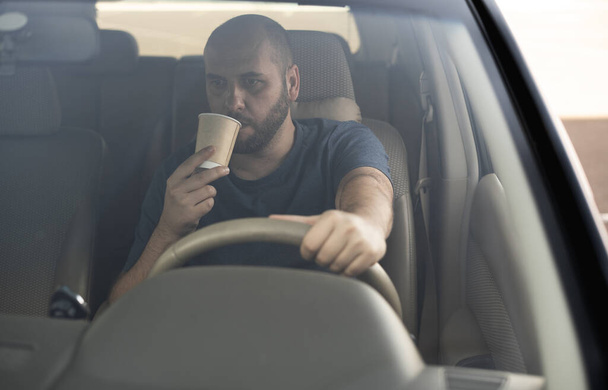 Milenyum adamı ya da şoförü kahve fincanı taşıyan bir sürücü. Ulaşım, araç ve insan konsepti. Uyuma ve sürme. - Fotoğraf, Görsel
