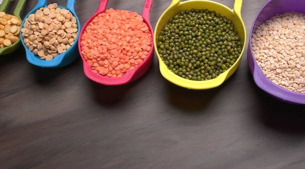 Неварені пульсації, зерна і насіння в барвистих мисках на дерев'яному фоні
 - Фото, зображення
